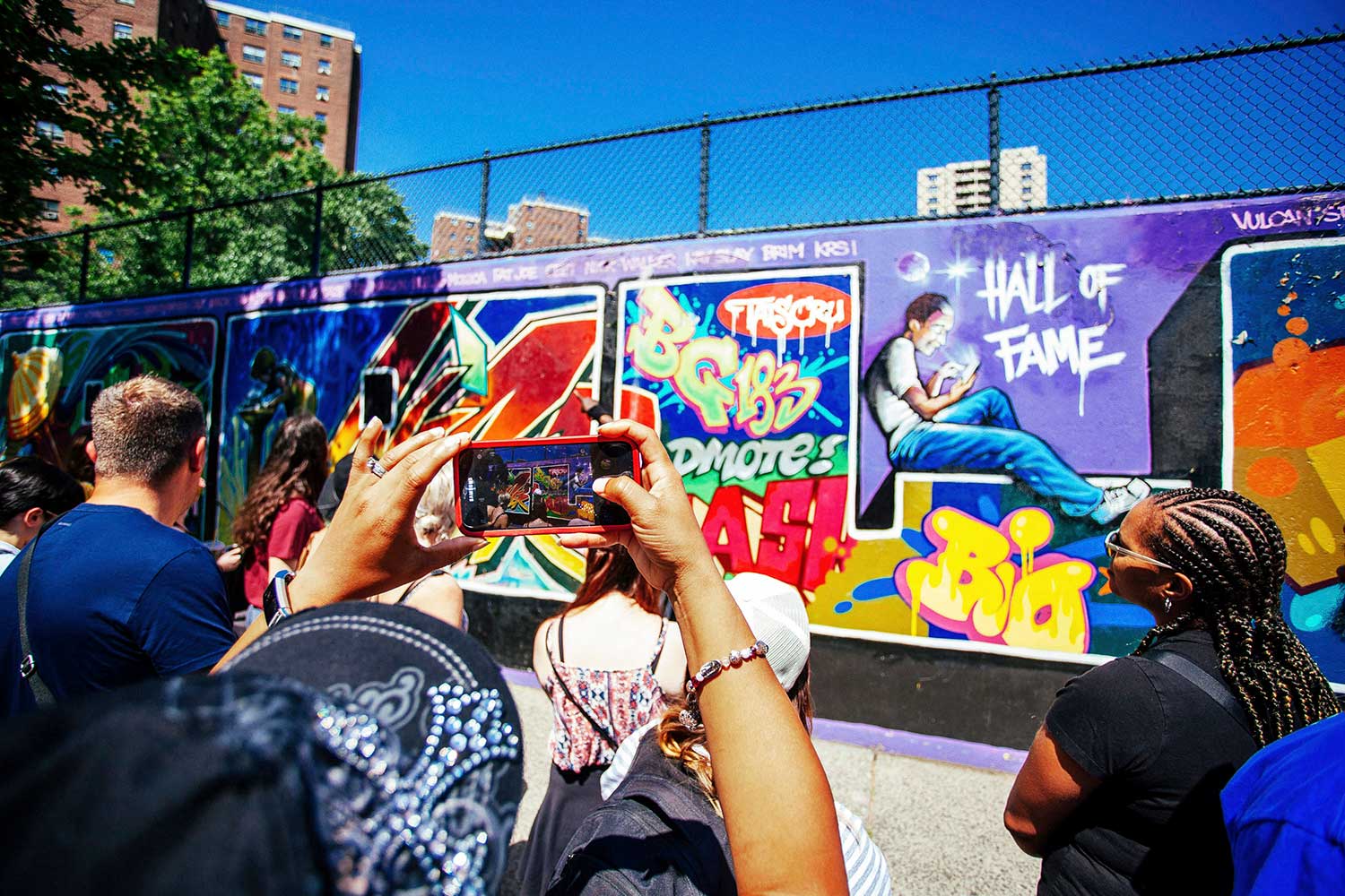 People using a cell phone to capture an image of a graffiti wall