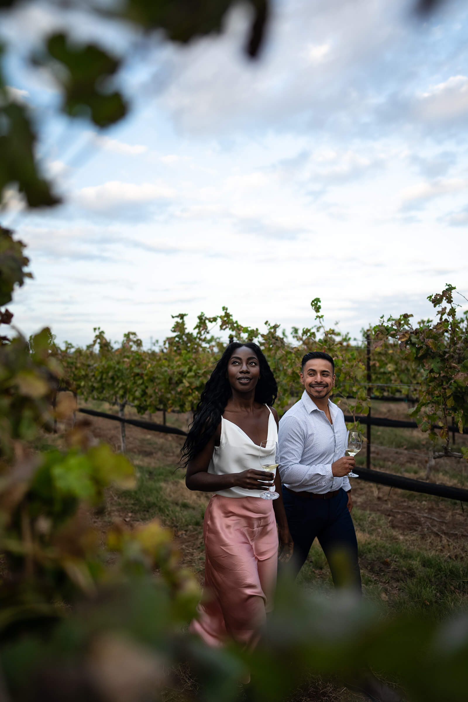 Two people with wine glasses in a vineyard