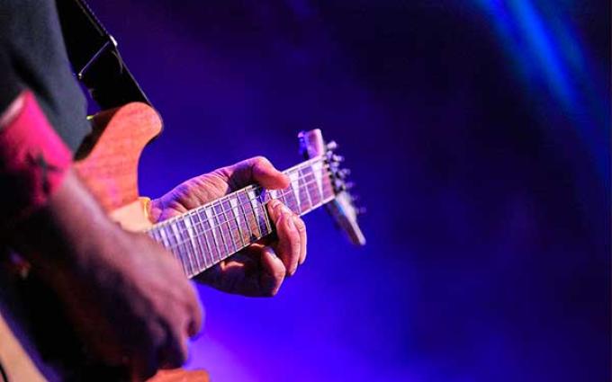 Close up of hands on the neck of a guitar