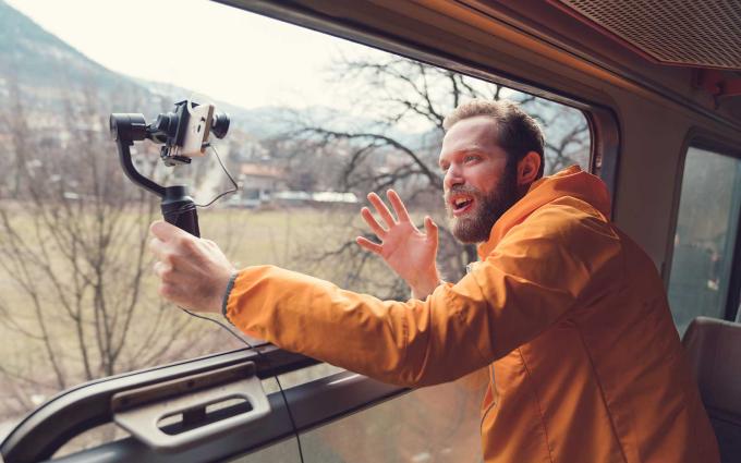 Man leaning out window with camera on pole