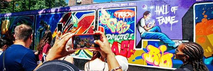 People using a cell phone to capture a graffiti wall